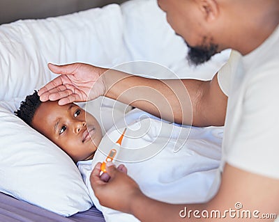 Sick little boy in bed while his father uses a thermometer to check his temperature. Black single parent feeling sons Stock Photo