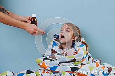 Sick little girl with common cold is sitting in bed, taking medicine Stock Photo