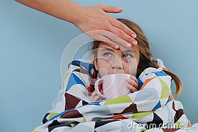 Sick little girl with common cold sitting in bed under blanket with warm tea Stock Photo