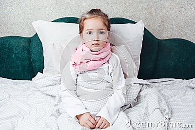 Sick little girl lying in the bed in pink scarf Stock Photo