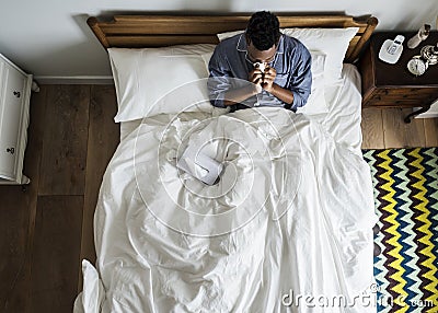 Sick man on bed blowing his nose Stock Photo