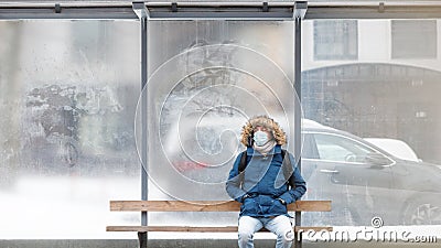 Sick man sitting alone on bench public transport, wearing mask Stock Photo