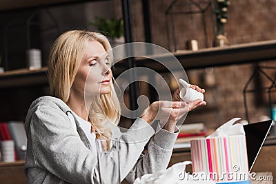 sick middle aged woman taking medicine while sitting Stock Photo