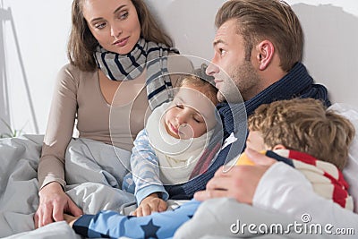 Sick parents and children lying in a bed with scarfs Stock Photo