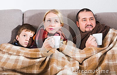 Sick parents and son under blanket Stock Photo