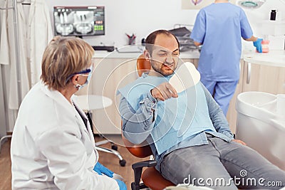 Sick patient inspecting teeth after dental surgery using mirror Stock Photo