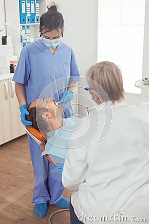 Sick patient lying on dental chair with open mouth for medical procedure Stock Photo