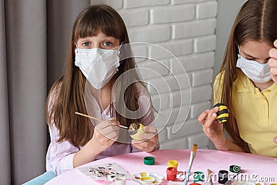 A sick quarantined child paints Easter eggs for the holiday Stock Photo