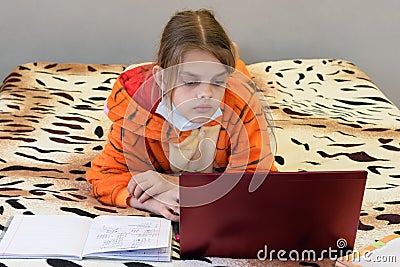 A sick quarantined girl learns remotely using a laptop Stock Photo