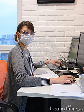 The sick quarantined girl works at the computer, looked into the frame Stock Photo