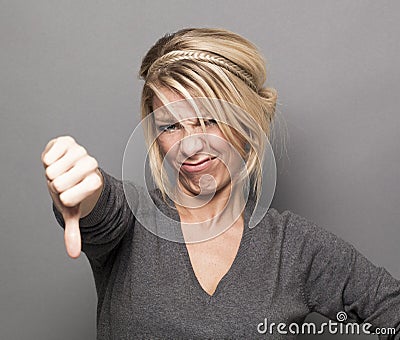 Sick 20s girl expressing repulsion with thumb down and grimace Stock Photo