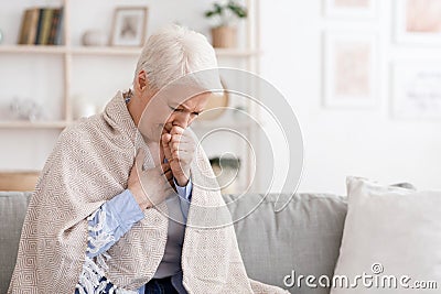 Sick Senior Woman Covered In Blanket Coughing Hard At Home Stock Photo