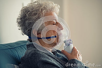 Sick senior woman making inhalation with nebulizer Stock Photo