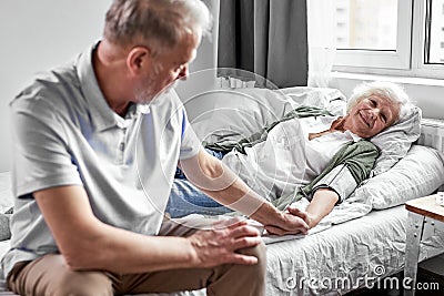 sick senior woman with her caring elderly husband sitting close to her Stock Photo