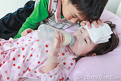 Sick sister lying and suck up milk on the bed, kindly brother keep vigil over a sick of closely. Stock Photo