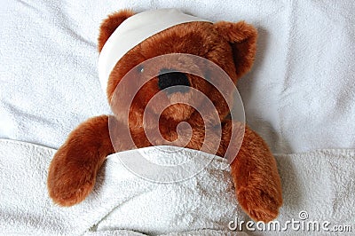 Sick teddy with injury in bed Stock Photo