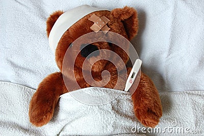 Sick teddy with injury in bed Stock Photo