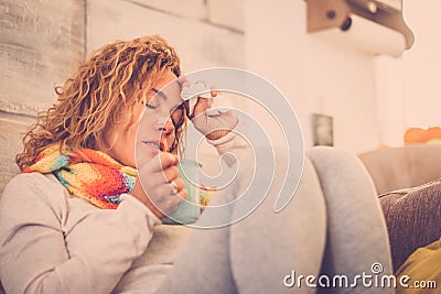 Sick and unwell young woman feeling wrong with flu and some virus on the sofa at home. Female with fever and headache feeling Stock Photo