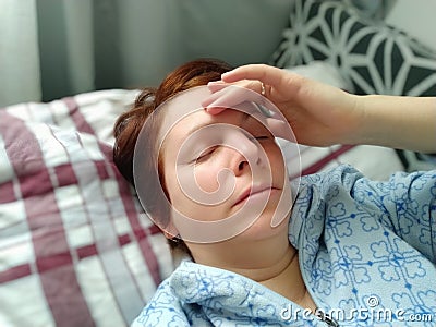 Sick woman in bed. Headache, runny nose and cold. Paleness of the face and faintness of the body. Feeling unwell. The Stock Photo