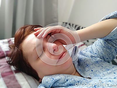 Sick woman in bed. Headache, runny nose and cold. Paleness of the face and faintness of the body. Feeling unwell. The Stock Photo