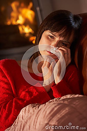 Sick Woman With Cold Resting By Cosy Log Fire Stock Photo