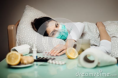 Sick woman with mask in quarantine bed self isolation.Coronavirus Covid-19 patient having pneumonia disease symptoms.Prevention Stock Photo