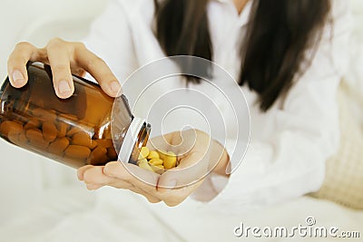 Sick woman sitting in bed, pouring antibiotics, treating infections, taking medicines. Stock Photo