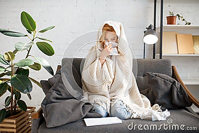 Sick woman sitting with kerchief under the blanket Stock Photo