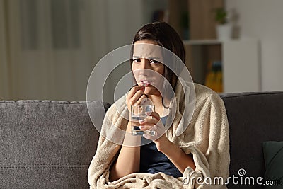 Sick woman taking painkiller pill looking at camera Stock Photo