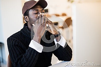 Sick young african-american businessman wearing suit caught cold sneezing in tissue working in office Stock Photo