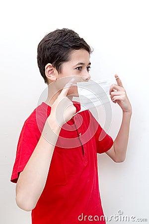 Sick young boy clutches his throat with face mask on. Stock Photo