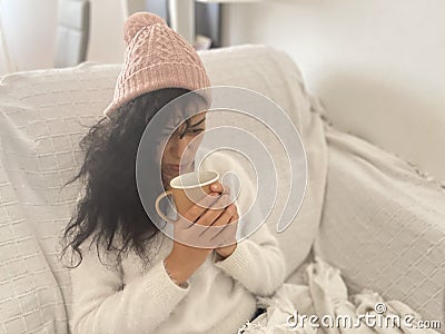 Sick young woman enjoying a hot drink, and warming her hands at home on a very cold winter day. Concept cold at home, sickness Stock Photo