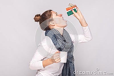 Sick young woman holding cup with tea, many pills, antibiotics. Stock Photo