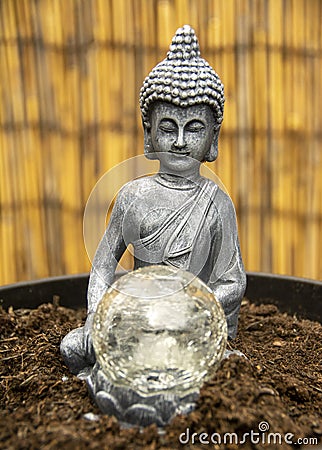 Siddharrtha Guautama with crystal ball on a cane fence. Stock Photo