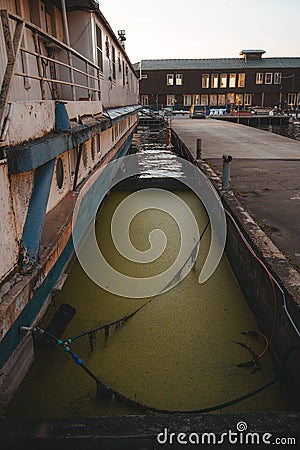 The side of the boat is on the pier. The green murk of the water. Bridge. Stock Photo