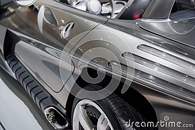 Side close up view from the back of modern roofless grey sport coupe car with mirror, chrome wheel disc and fuel tank Stock Photo