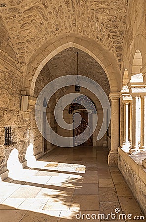 Side entrance with a decorative figure of a peacemaker on the wall and a bell on the floor to the side of the Chapel of Saint Editorial Stock Photo