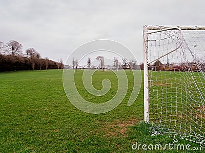 Side of a football goal post with net in focus. Training pitch out of focus. Soccer theme background Stock Photo