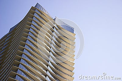 Side low angle view of a modern corporate high-rise office building with yellowish overhangs in each floor. Stock Photo