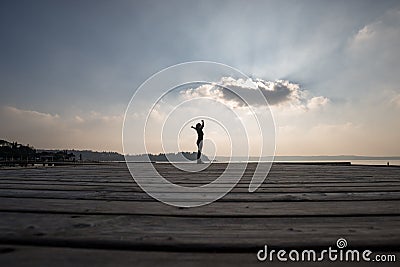 Side low angle view of a woman with arms outspread against cloud Stock Photo