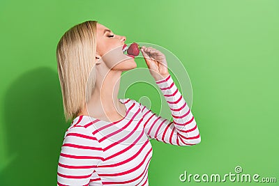 Side photo of nice young lady blonde bob hair bite small piece strawberry summertime sweet ripe fruit isolated on green Stock Photo