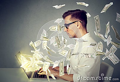 Side profile young man using a laptop computer making money Stock Photo