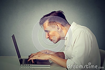 Side profile young man working on computer sitting at desk Stock Photo