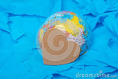 Side shot of a glove hemisphere with heart-shaped paper on the colored paper ground. Stock Photo