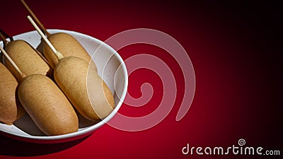 Side shot view of plate with five corn dogs spinning on red background. Stock Photo