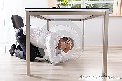 Afraid Businessman Hiding Under Table Stock Photo