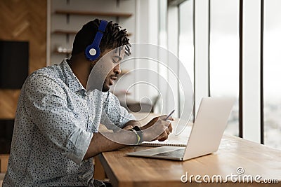 Side view African American man wearing headphones taking notes Stock Photo