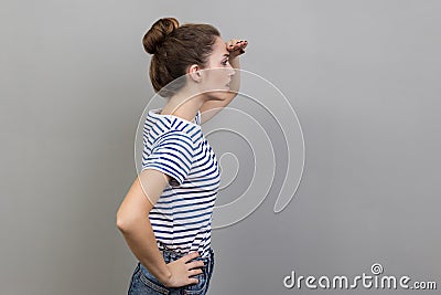 Side view of ambitious woman watching far away with hand above eyes, looking forward to future. Stock Photo