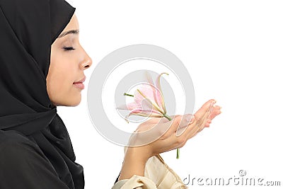 Side view of an arab woman wearing a hijab smelling a flower Stock Photo