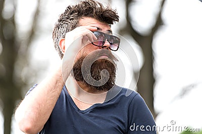 Side view bearded man adjusting his sunglasses. Stylish young man with well-trimmed beard and mustache enjoying warm Stock Photo